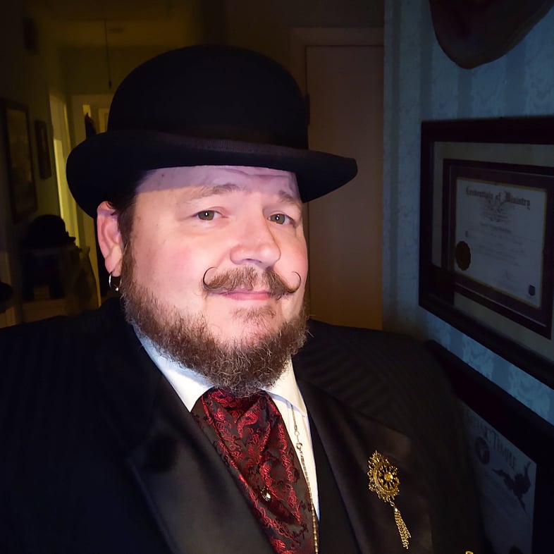 a man in a fine bowler hat squints at a bright light behind the camera